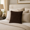 Luxury brown velvet throw pillow on a cozy bed with neutral bedding and bedside lamp