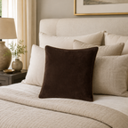 Luxury brown velvet throw pillow on a cozy bed with neutral bedding and bedside lamp