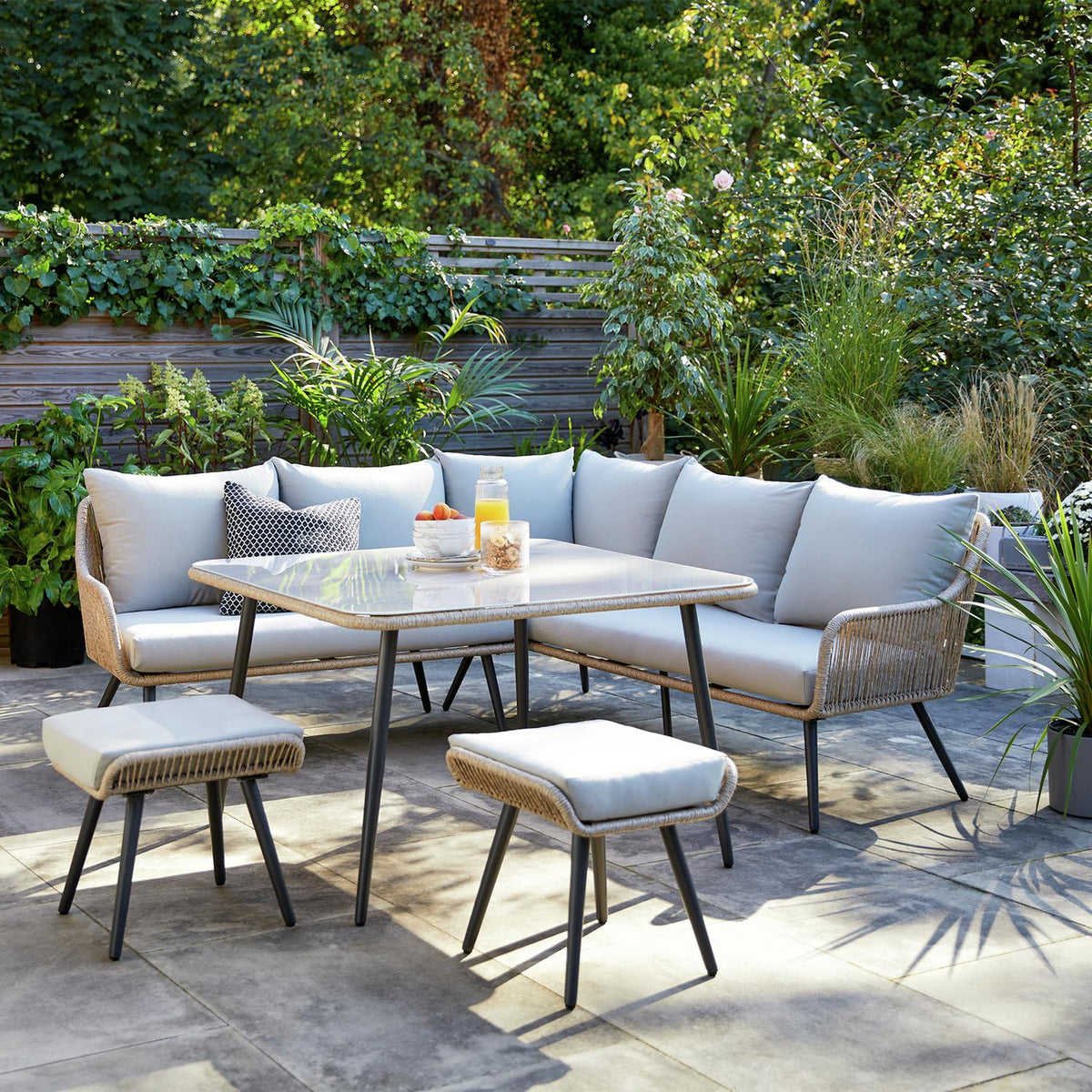 Luxury outdoor wicker sofa set with glass table and cushions on patio, perfect for garden dining