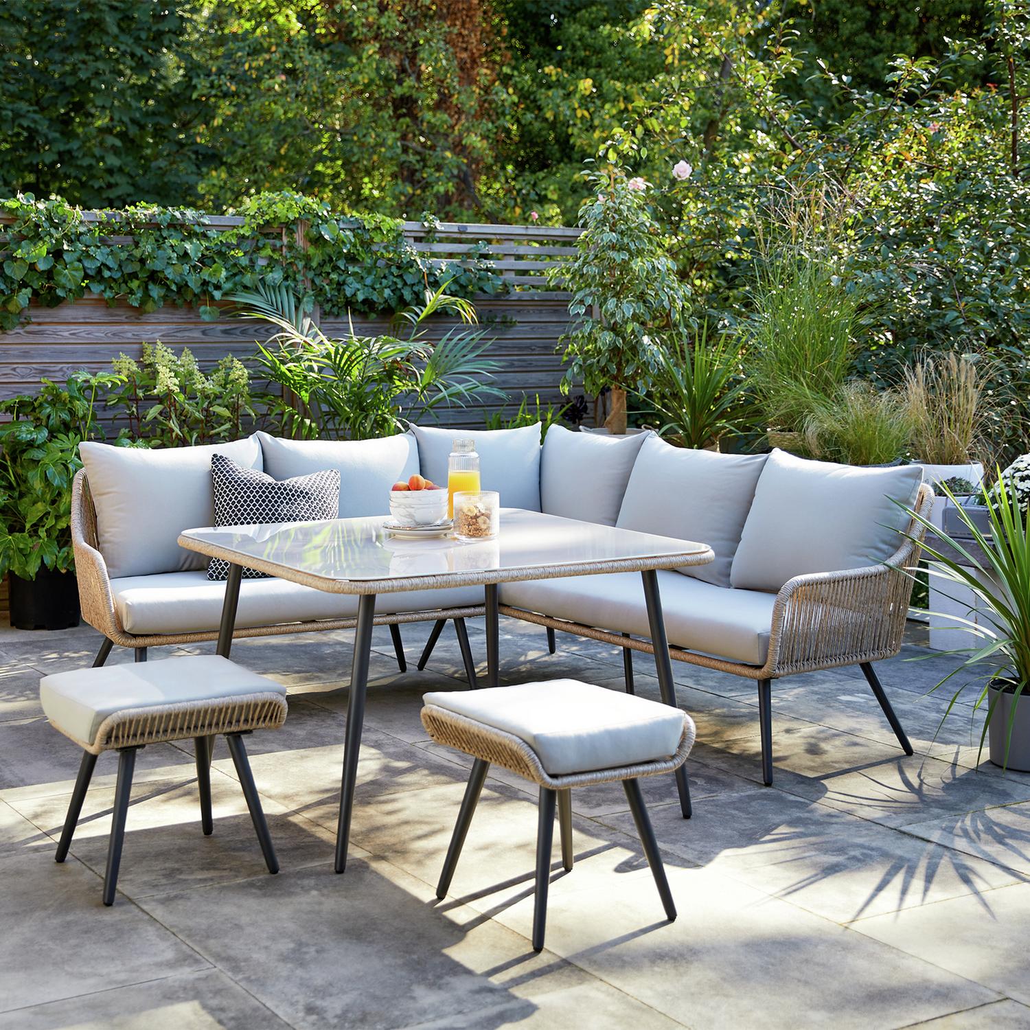 Luxury outdoor wicker sofa set with glass table and cushions on patio, perfect for garden dining