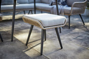 Woven outdoor stool with cream cushion and black legs on patio, matching luxury garden furniture set