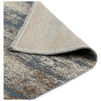 Blue and beige patterned area rug with textured weave and folded corner detail