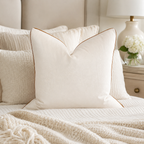 Luxury cream velvet pillow with gold piping on a cozy bed, perfect for elegant bedroom decor