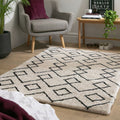 Cream geometric rug with black pattern in modern living room, styled with grey armchair and plants