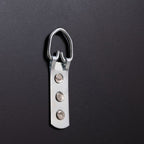 Metal D-ring hardware with three rivets on dark surface, for furniture assembly