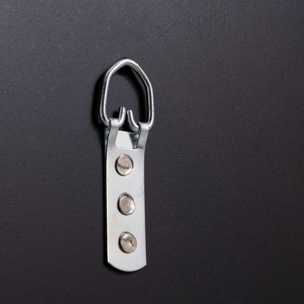 Metal D-ring hardware with three rivets on dark surface, for furniture assembly