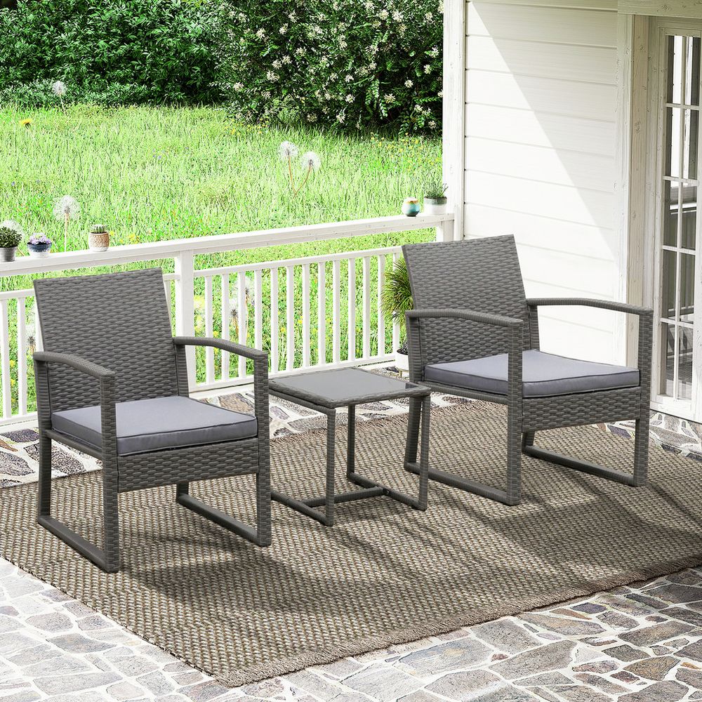 Grey wicker outdoor patio furniture set with armchairs and side table on stone deck