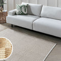 Modern white sofa with green leaf pillow on textured rug in living room