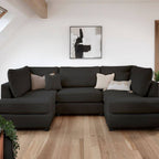 Modern black corner sofa with neutral cushions in a bright living room with wooden floor