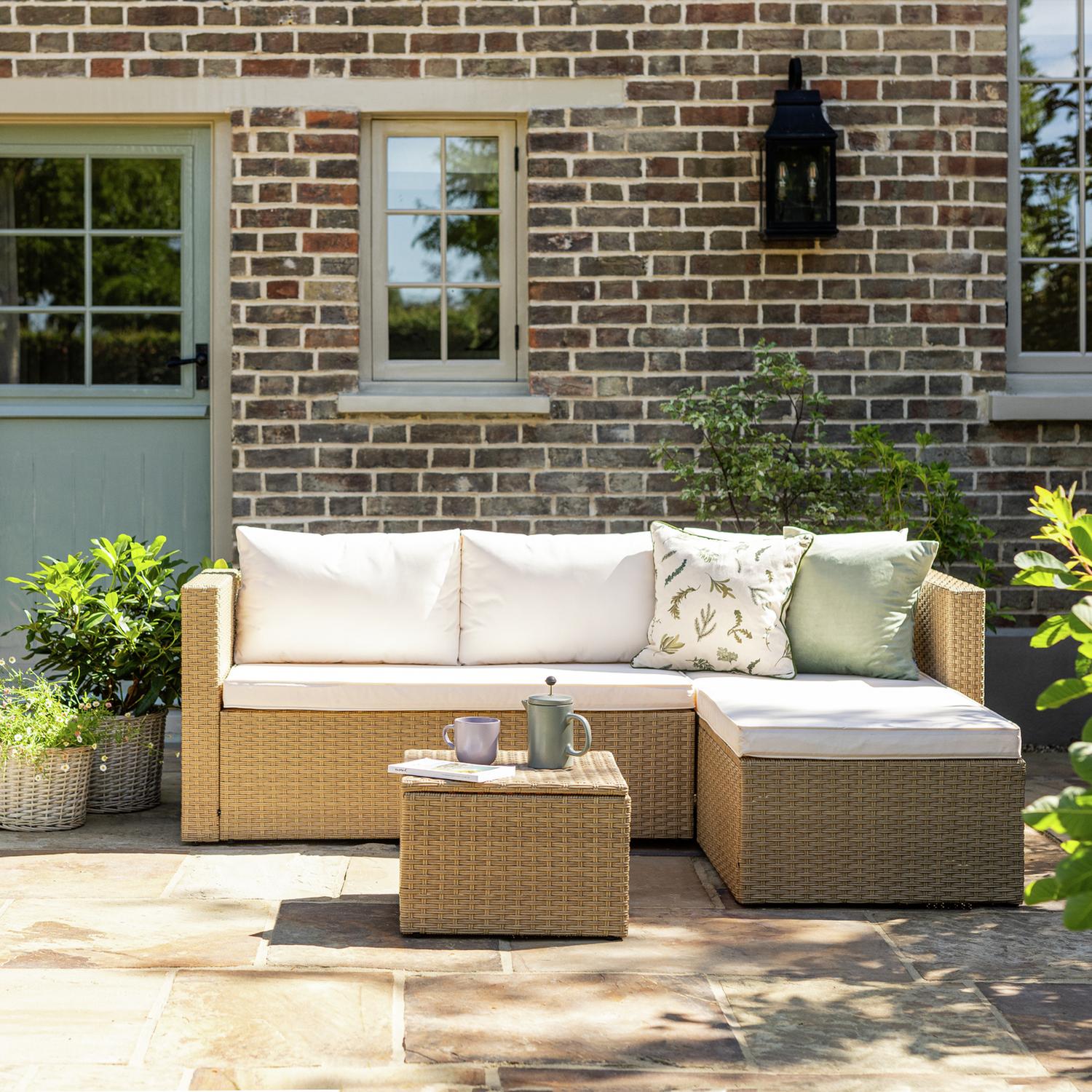 Luxury outdoor wicker sofa set with white cushions on stone patio, perfect for garden relaxation