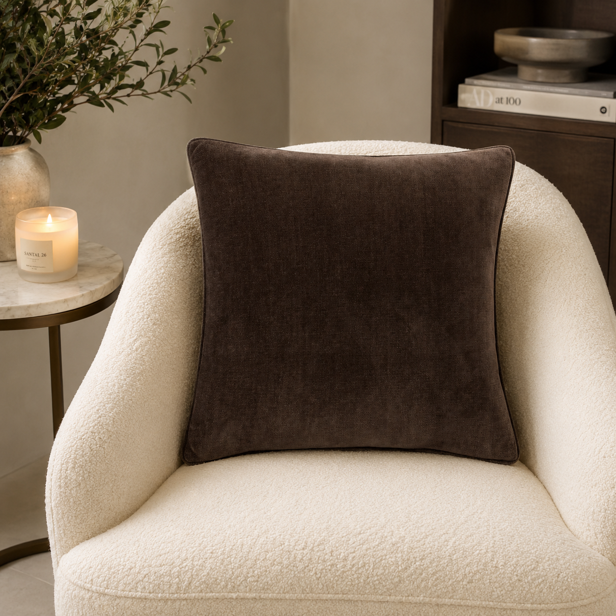 Luxury brown velvet cushion on cream bouclé armchair, styled with candle and greenery for cozy living room decor