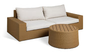 Wicker outdoor sofa with cream cushions and matching round coffee table for patio or garden use
