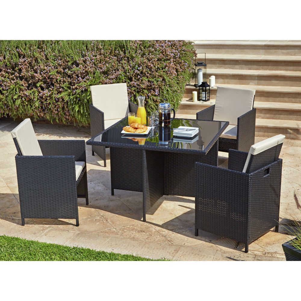 Black wicker outdoor dining set with cream cushions, glass table, and breakfast setup on patio