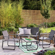 Modern outdoor patio furniture set with sofa, chairs, and coffee table on green rug in garden