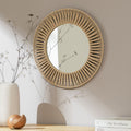 Round woven rope wall mirror with sunburst design, styled with dried flowers and home decor