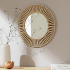 Round woven rope wall mirror with sunburst design, styled with dried flowers and home decor
