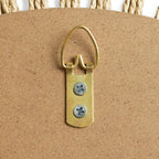 Brass hanging loop with screws on corkboard, natural rope border detail
