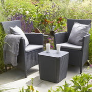 Grey wicker outdoor chairs with cushions and side table in garden setting