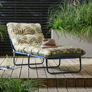 Tropical leaf print outdoor lounge chair on wooden deck with hat and drink, perfect for patio relaxation.
