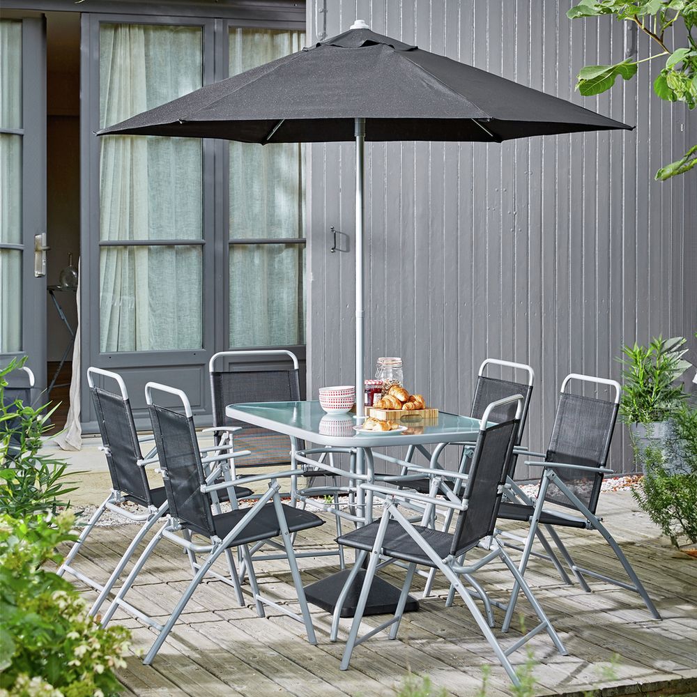 Outdoor dining set with black umbrella, glass table, and 6 chairs on wooden patio
