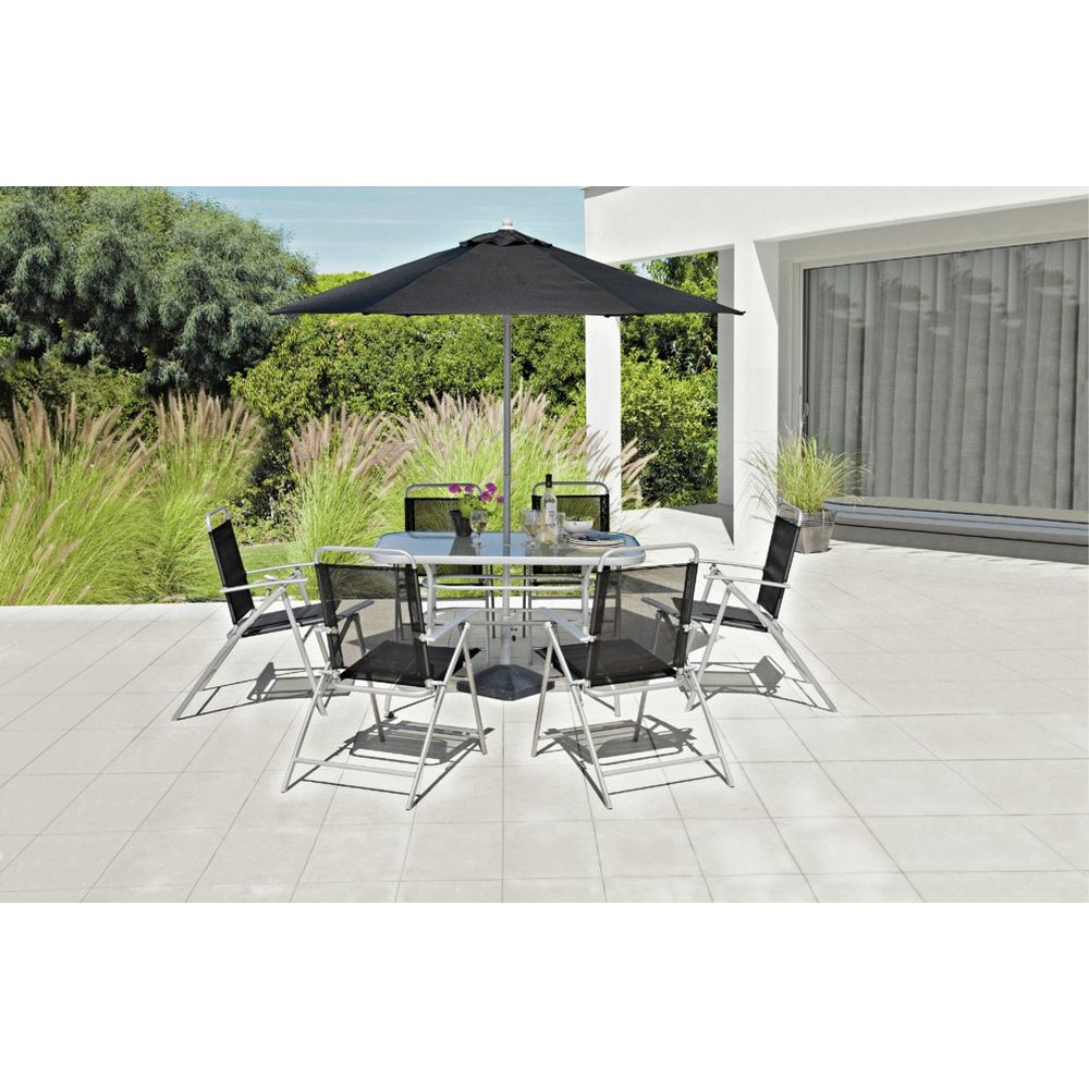Modern outdoor dining set with glass table, black chairs, and umbrella on patio