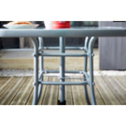 Grey metal outdoor table with curved legs on wooden deck, perfect for patio dining