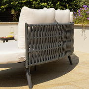 Modern outdoor sofa with woven grey frame and cream cushions on patio