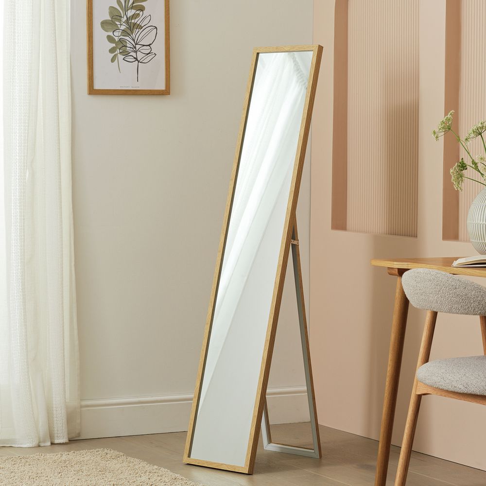 Full-length wooden floor mirror in modern bedroom with neutral decor and natural light