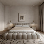 Modern beige upholstered bed in a minimalist bedroom with neutral decor and pendant lighting