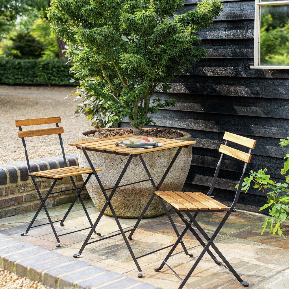 Compact outdoor bistro set with wooden slats and black metal frame on patio, perfect for garden dining