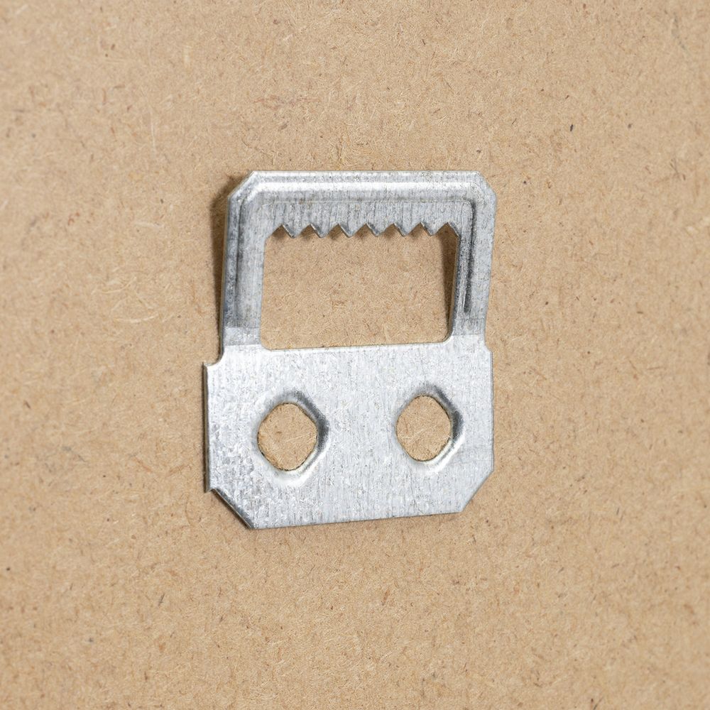 Metal sofa bed frame connector with two holes and serrated edge on cardboard background