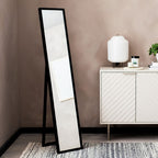 Black full-length floor mirror with A-frame stand in modern living room, beside white sideboard and lamp