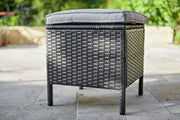 Grey wicker outdoor ottoman with cushion on patio, perfect for garden seating