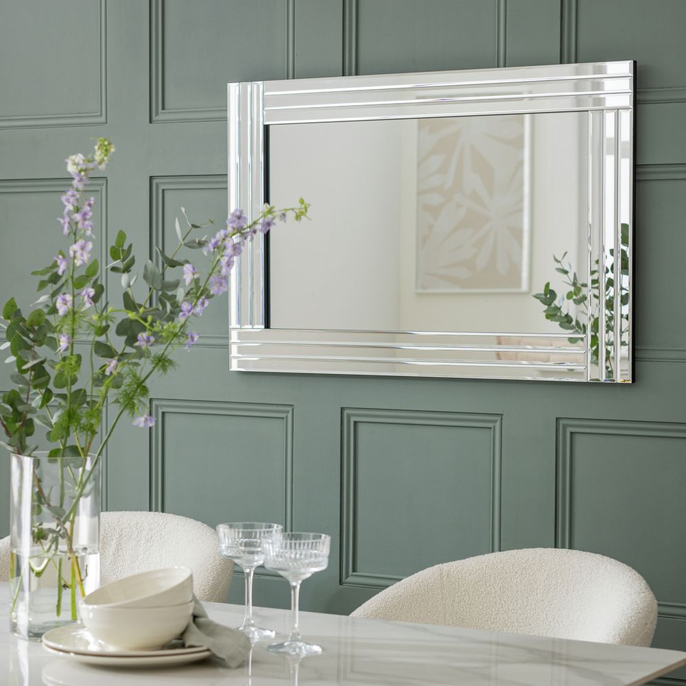 Luxury chrome-framed mirror above dining table with floral centerpiece, modern home decor