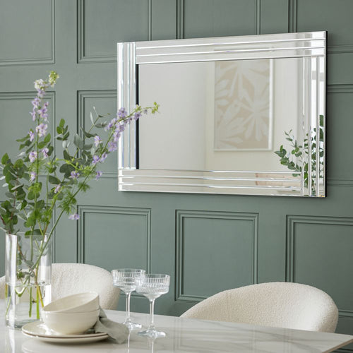 Luxury chrome-framed mirror above dining table with floral centerpiece, modern home decor