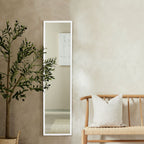 White full-length mirror with slim frame, styled with olive tree and wooden bench in modern living room