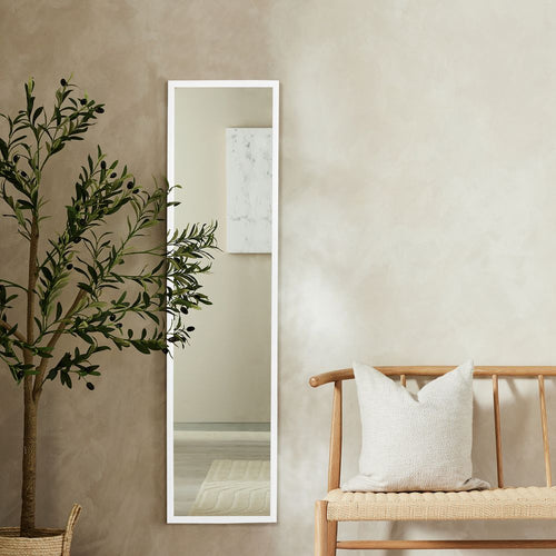 White full-length mirror with slim frame, styled with olive tree and wooden bench in modern living room