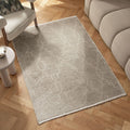 Beige geometric pattern rug on herringbone wood floor beside modern sofa and armchair