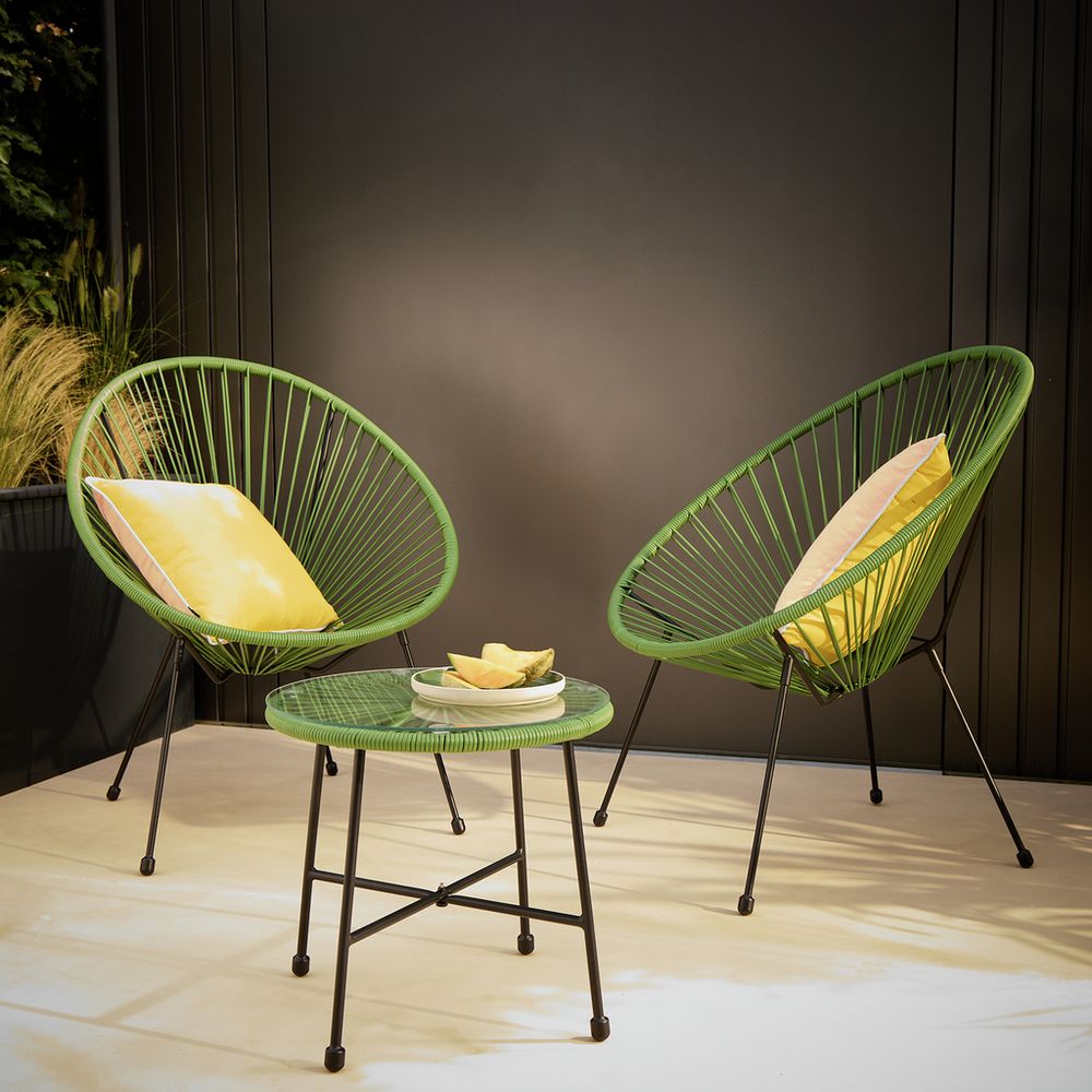Green outdoor wicker chairs with yellow cushions and matching side table on patio