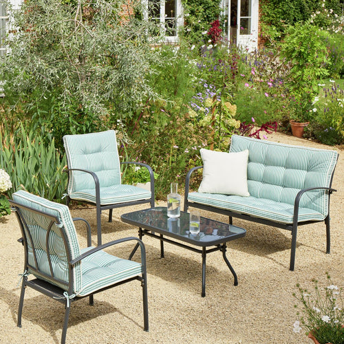 Striped outdoor garden furniture set with sofa, chairs, and glass table in lush backyard setting