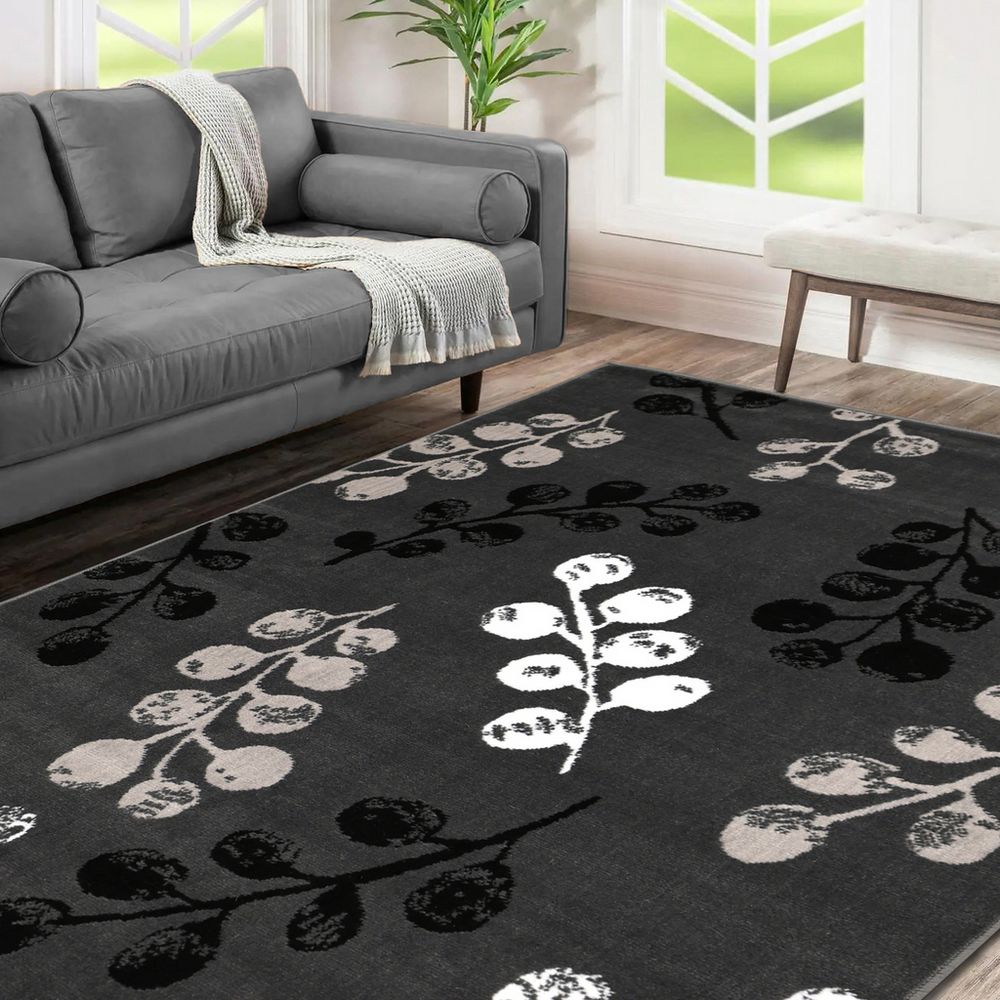 Black and white floral rug with berry pattern in modern living room, styled with gray sofa and natural light