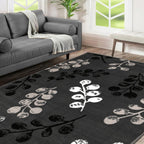 Black and white floral rug with berry pattern in modern living room, styled with gray sofa and natural light