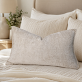 Luxury beige textured lumbar pillow on a cozy bed with neutral bedding and headboard