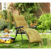 Yellow zigzag pattern outdoor lounge chair on grass with garden backdrop