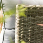 Close-up of woven rattan outdoor sofa with grey cushion, perfect for luxury garden furniture