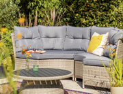 Grey outdoor wicker sofa with cushions and yellow pillow in garden setting