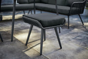 Black outdoor wicker footstool with cushion, modern patio furniture set on stone tiles