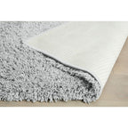 Soft grey shaggy rug with textured cream backing on light wood floor
