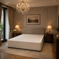 Luxury upholstered bed frame in elegant bedroom with chandelier and dark wood nightstands