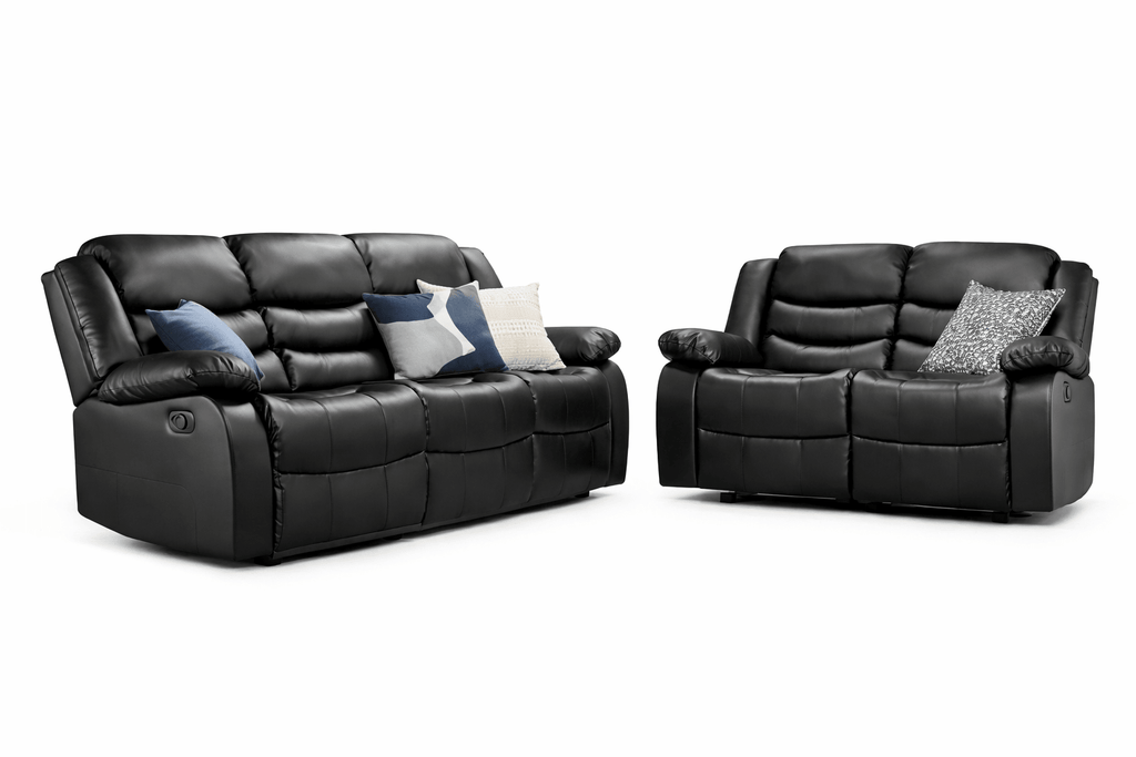 Black leather recliner sofa and loveseat set with decorative accent pillows on white background.